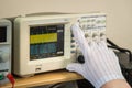 Modern oscilloscope, man`s hand adjusting wave signals, closeup