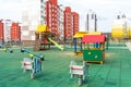 A modern outdoor playground in the courtyard of a building. Colorful children\'s swings and slides for recreation and games Royalty Free Stock Photo