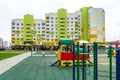 A modern outdoor playground in the courtyard of a building. Colorful children\'s swings and slides for recreation and games Royalty Free Stock Photo