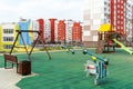 A modern outdoor playground in the courtyard of a building. Colorful children\'s swings and slides for recreation and games Royalty Free Stock Photo