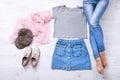 Template shirt. Modern outfit with different accessories and female legs in jeans on white wooden floor. Top view and copy space.