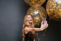 Modern party time of young gorgeous woman in black luxury dress, with long curly blonde hair making selfie with big Royalty Free Stock Photo