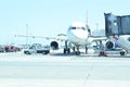 Modern passenger airplane parked to terminal building gate at airside apron of airport with airplane parts jet engine