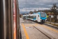 Modern passenger train is approaching train station in city suburbs. Cloudy and rainy weather with a train on the platform Royalty Free Stock Photo