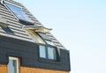 Modern passive house roof with attic skylight windows, solar water heater, solar panels, asphalt shingles