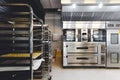 Modern pastry kitchen decorated in black, white and steel with baking machine, oven, conveyor, production line, mixer.