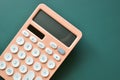 modern peach colour pastel calculator and white button on green background, business and finance concept Royalty Free Stock Photo