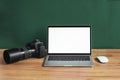 Modern photographer workplace with computer, DSLR camera and lenses. Laptop with the blank white screen on the wooden office table Royalty Free Stock Photo