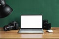 Modern photographer workplace with computer, DSLR camera and lenses. Laptop with the blank white screen on the wooden office table Royalty Free Stock Photo