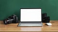 Modern photographer workplace with computer, DSLR camera and lenses. Laptop with the blank white screen on the wooden office table Royalty Free Stock Photo