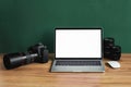 Modern photographer workplace with computer, DSLR camera and lenses. Laptop with the blank white screen on the wooden office table Royalty Free Stock Photo