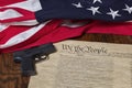 Modern pistol with thirteen star flag and the constitution of the United States on dark wood background