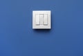 Modern plastic light switch on blue background. Space for text Royalty Free Stock Photo