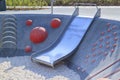 modern Playground with a metal slide inscribed in a contemporary landscape design stairs made of red hemispheres, made on the Royalty Free Stock Photo