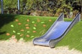 modern playground with a metal slide inscribed in the landscape design with a ladder of plastic shells made on the hillside Royalty Free Stock Photo