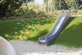 modern playground with metal slide inscribed in landscape design with ladder of plastic shells made on hillside Royalty Free Stock Photo