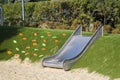 modern playground with a metal slide inscribed in the landscape design with a ladder of plastic shells made on the hillside Royalty Free Stock Photo