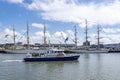 A modern police boat passes the Tallships Mircea and Shabab Oman II, in the harbour of Scheveningen during the Sail on Scheveninge