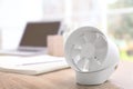 Modern portable fan on wooden table in office, space for text. Summer heat Royalty Free Stock Photo