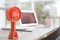 Modern portable fan on wooden table in office, space for text. Summer heat