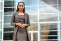 Modern portrait of African American female business person standing by office building, architecture firm, law, finance or other p