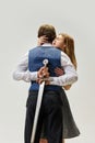 Modern portrait of young couple in codependent hypertrophied toxic relationship. Woman hugs man with sword behind his