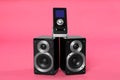 Modern powerful audio speakers with remote on pink background Royalty Free Stock Photo