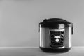 Modern powerful multi cooker on table against grey background.