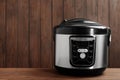 Modern powerful multi cooker on table against wooden background.