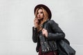 Modern pretty stylish hipster young woman in a fashionable hat in vintage dark sunglasses in a black jacket Royalty Free Stock Photo