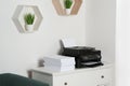 Modern printer and paper sheets on white chest of drawers Royalty Free Stock Photo