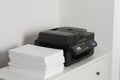 Modern printer and paper sheets on white chest of drawers Royalty Free Stock Photo