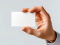 Businessman holding a blank white card between fingers with soft gray background for professional branding or personal information Royalty Free Stock Photo