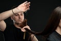 Modern professional man working as hairdresser and cutting hair tips of a female customer in beauty salon Royalty Free Stock Photo