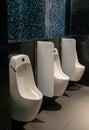 Modern public wc in  black and blue colors interior space. Ceramic urinal in bathroom Royalty Free Stock Photo