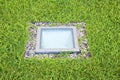 Modern quadrangular metal spotlight led lamp for outdoor use with square shape recessed in a grass floor Royalty Free Stock Photo