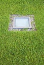 Modern quadrangular metal spotlight led lamp for outdoor use with square shape recessed in a grass floor Royalty Free Stock Photo