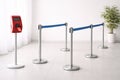 A Modern Queue Management System Featuring Red Ticket Kiosk and Blue Rope Barriers in an Royalty Free Stock Photo