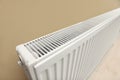 Modern radiator on beige wall, closeup. Central heating system