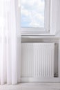 Modern radiator on wall under window indoors. Central heating system Royalty Free Stock Photo