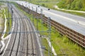 Modern railway route and highway separated by fence in countryside Royalty Free Stock Photo