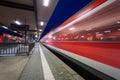 Modern railway station with high speed passenger train on railroad track in motion at night Royalty Free Stock Photo