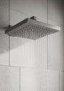 Modern rainfall shower head with water streams in minimalist bathroom setting Royalty Free Stock Photo