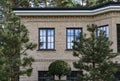 Fragment of modern red brick wall house surrounded of pine trees in sunny day. Royalty Free Stock Photo