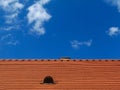 modern red brown sloped clay roof with vent under blue sky