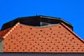 Red clay roof tiles on sloped house roof. galvanized metal flashing. metal snow breakers.