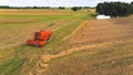 Modern red combine harvester working on agricultural field and collecting rapeseed crops. Aerial drone view. Summertime. Royalty Free Stock Photo