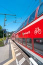 Modern red double deck local S1 train at Kurort Rathen village train station near Bastei sandstone pillars in the national park