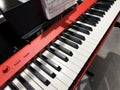 Modern red synthesizer with white and black keys and notes mounted on panel for easy playing. Electronic music playback. Choosing Royalty Free Stock Photo