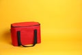 Modern red thermo bag on yellow background. Space for text Royalty Free Stock Photo